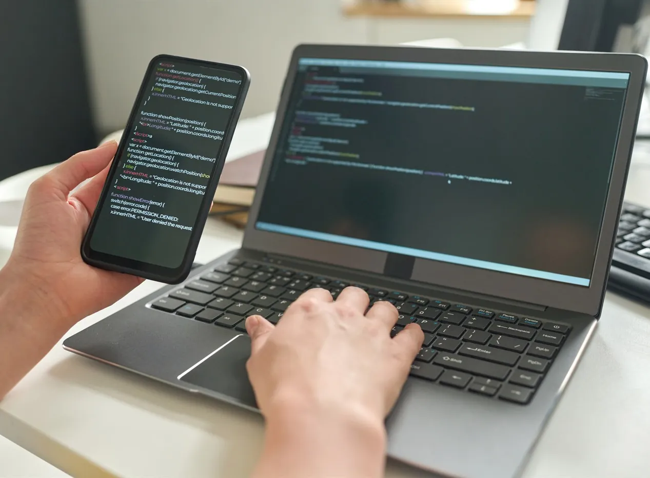 Developer testing a native Android app on a phone beside a laptop
